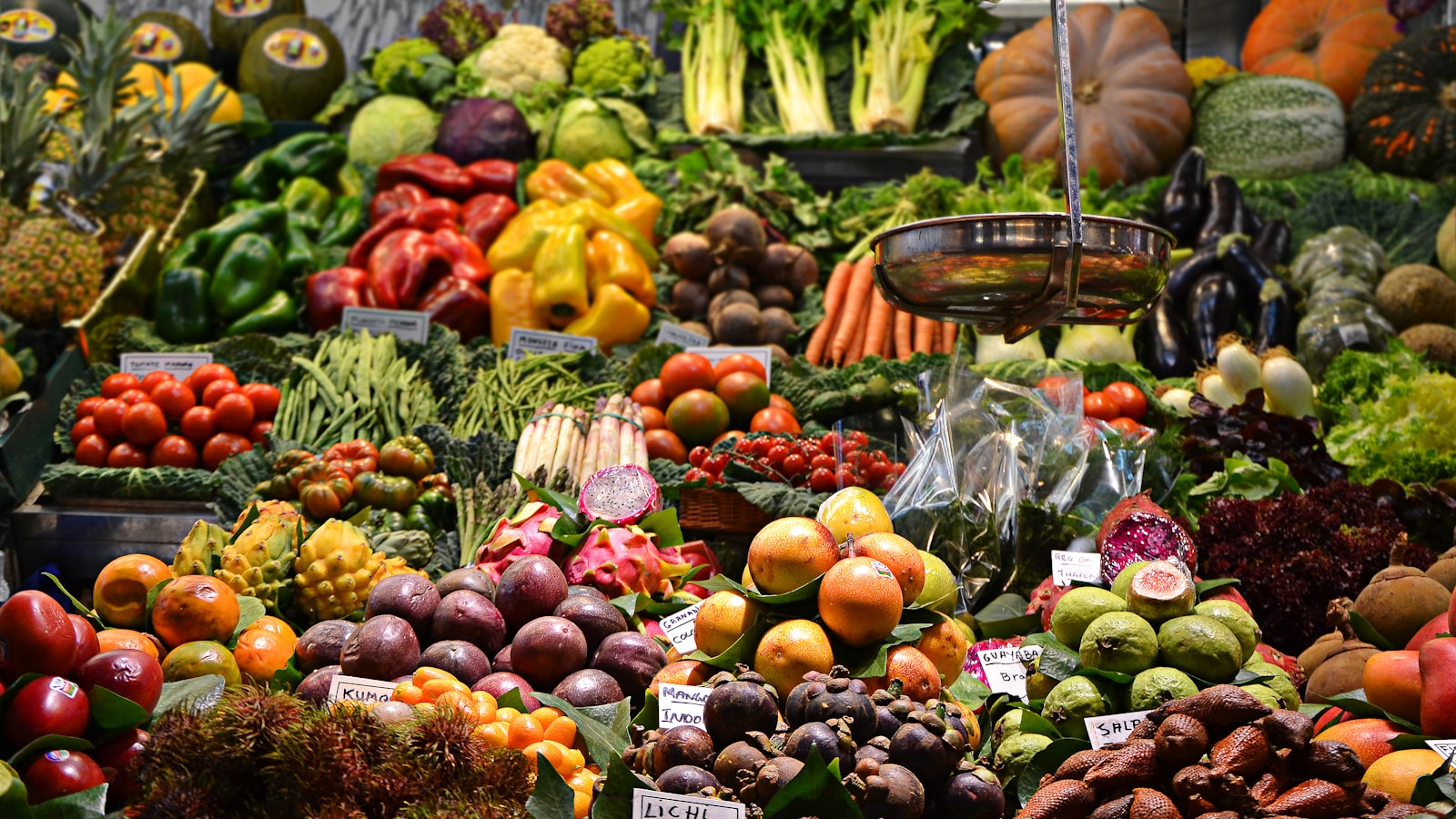 Outdoor farmers market stall piled with crates of fresh fruit and vegetables