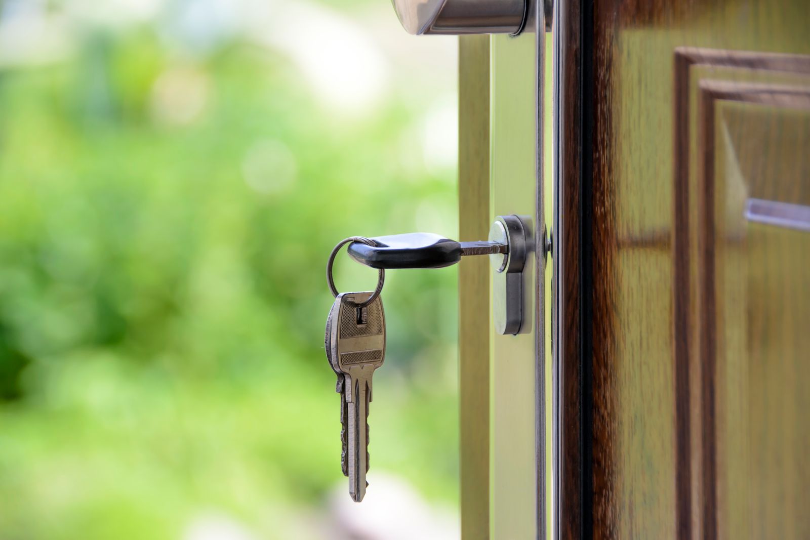 Brass house keys on a metal ring lying on a wooden surface
