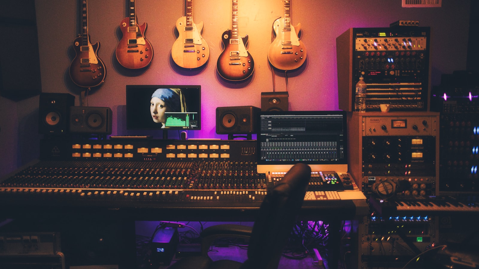 Close view of a large audio mixing console with rows of faders, knobs, and channel lights