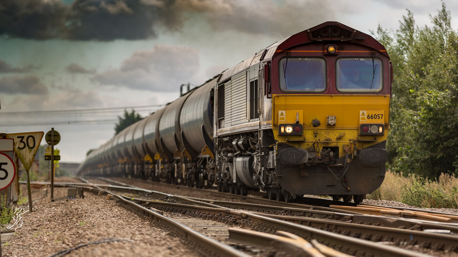 Parallel steel railway tracks converging toward a bright horizon under an open sky