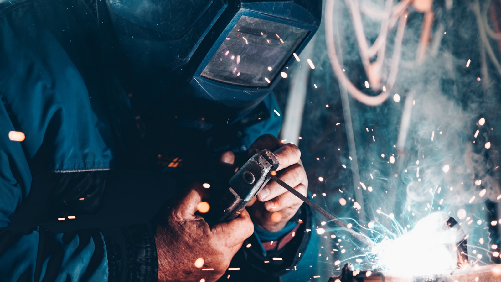 Bright sparks flying from an angle grinder on a metal workpiece in a dim workshop