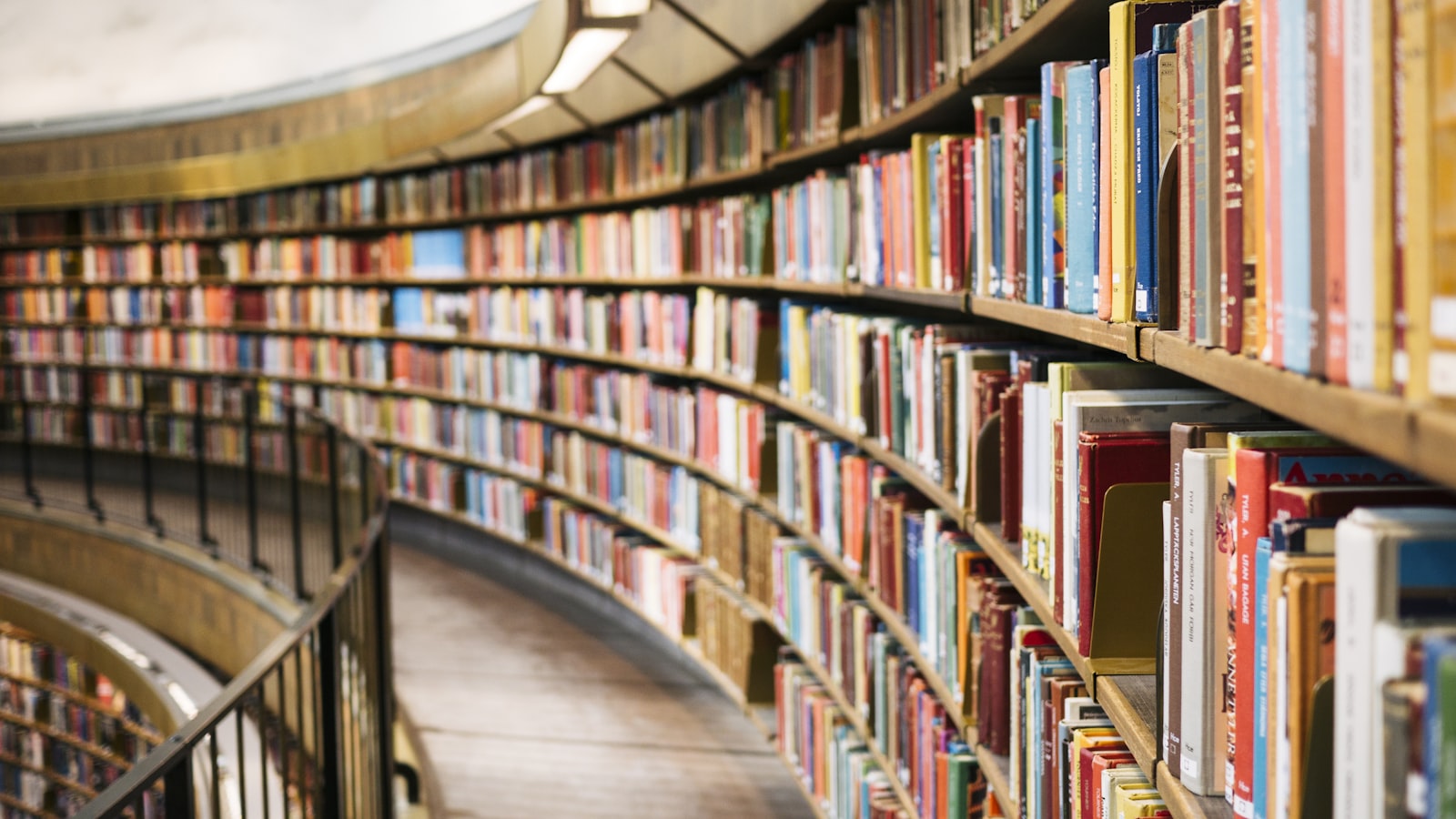Long aisle of a library with tall wooden shelves packed with hardcover books