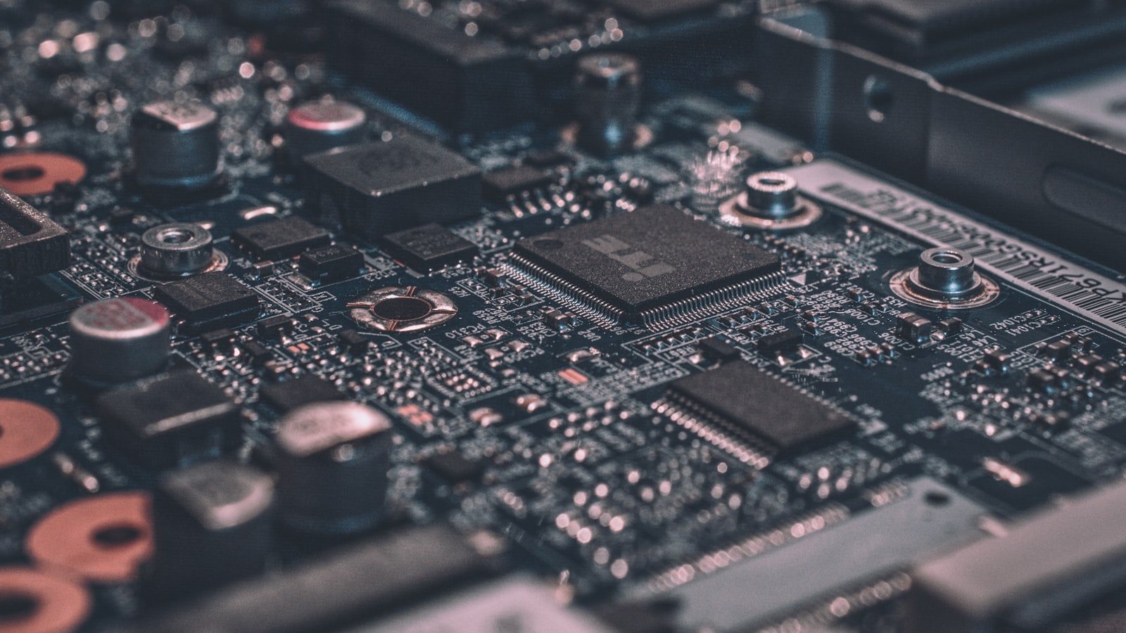Close-up of a green printed circuit board with solder traces, chips, and gold contacts